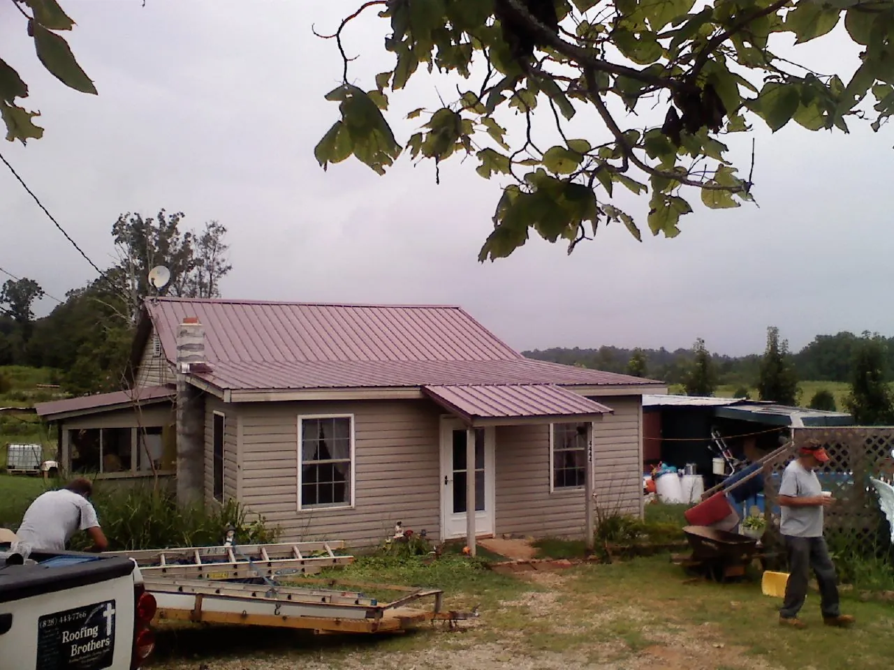 Crew finishing a mauve metal roof on a small farmhouse in Meridian