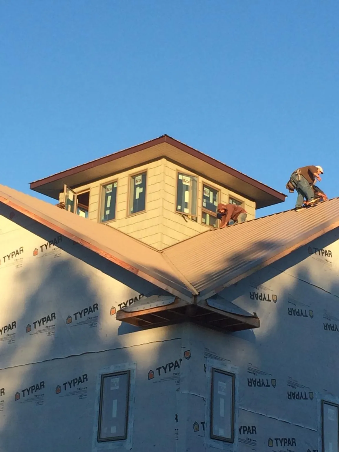Roofers working around a rooftop cupola on a new metal roof at sunset — Roof Waterproofing in Meridian by Roofing Brothers